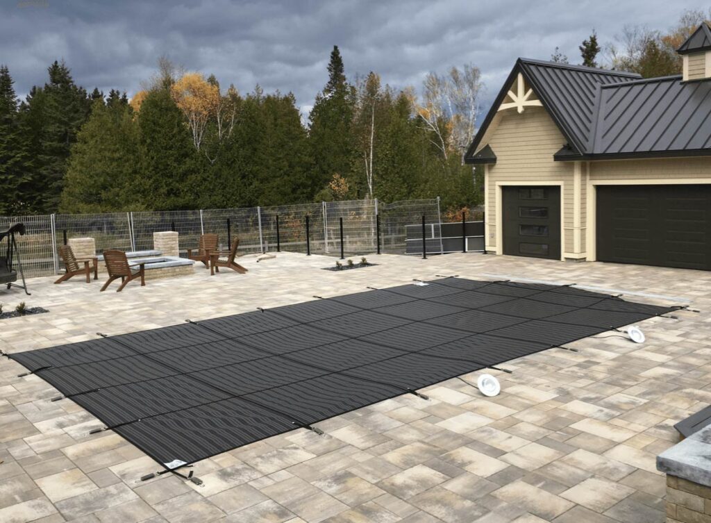Winter pool cover on patio with Adirondack chairs and garage in background