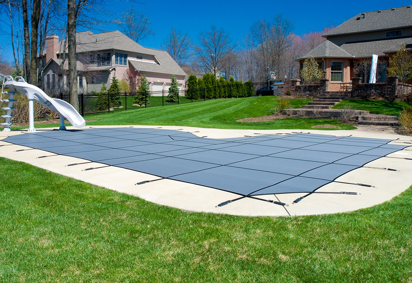 Covered swimming pool with water slide in backyard of suburban home