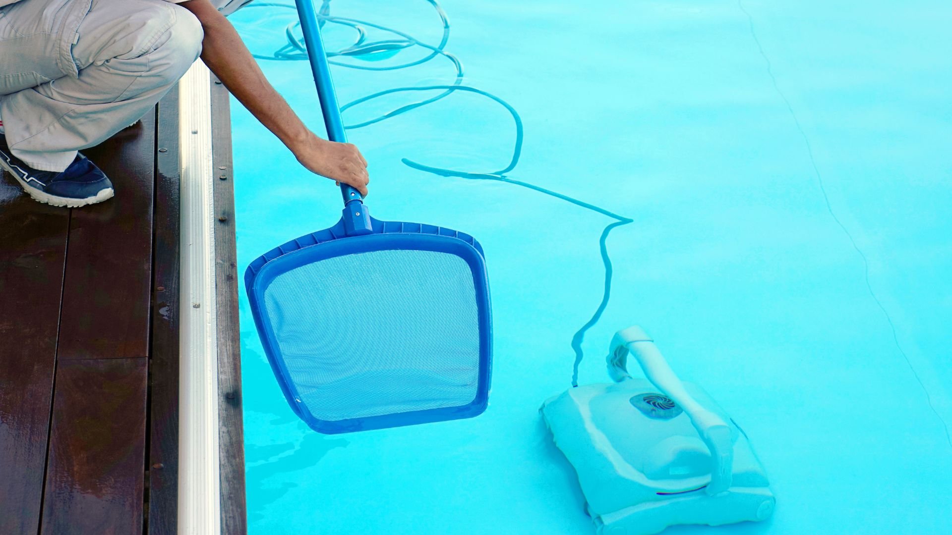 Pool cleaning net and automatic robot cleaner on bright blue water
