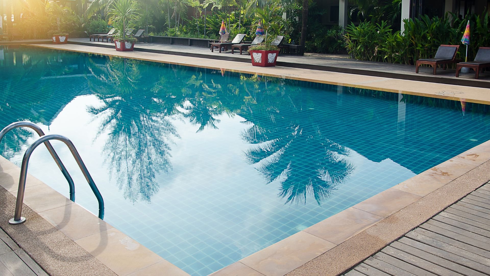 Tropical pool with palm tree reflections and lounge chairs surrounding it