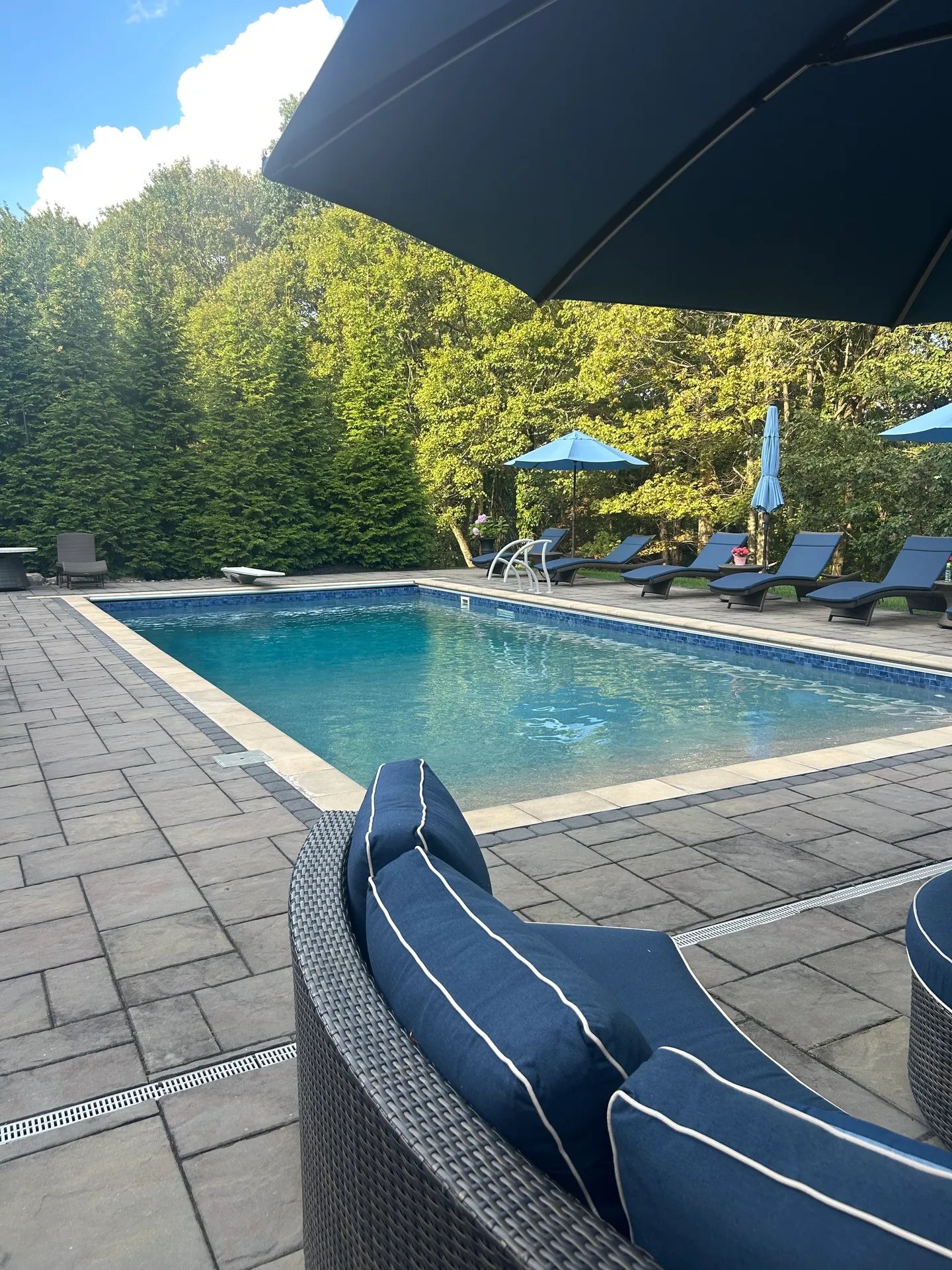Backyard swimming pool with lounge chairs and blue umbrellas