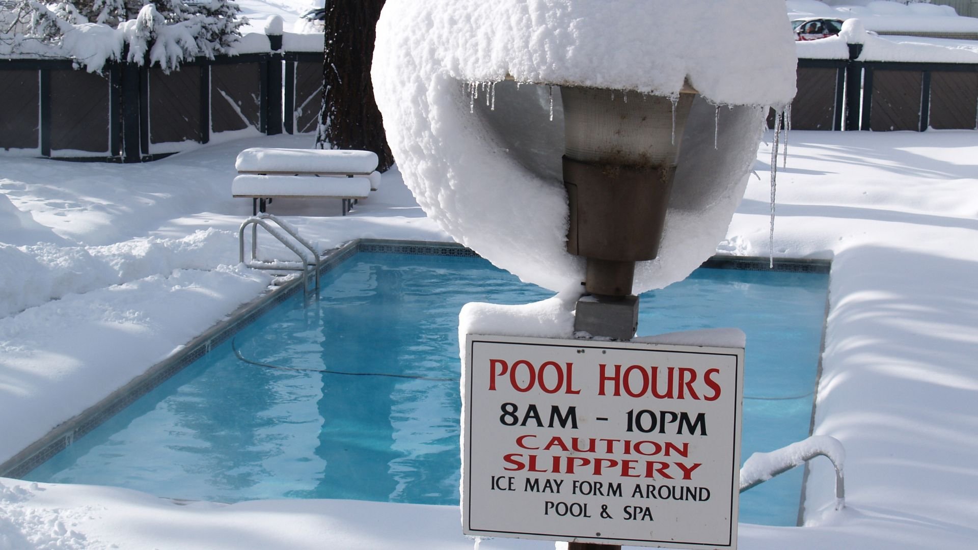Snowy pool with icy sign warning of slippery conditions during winter
