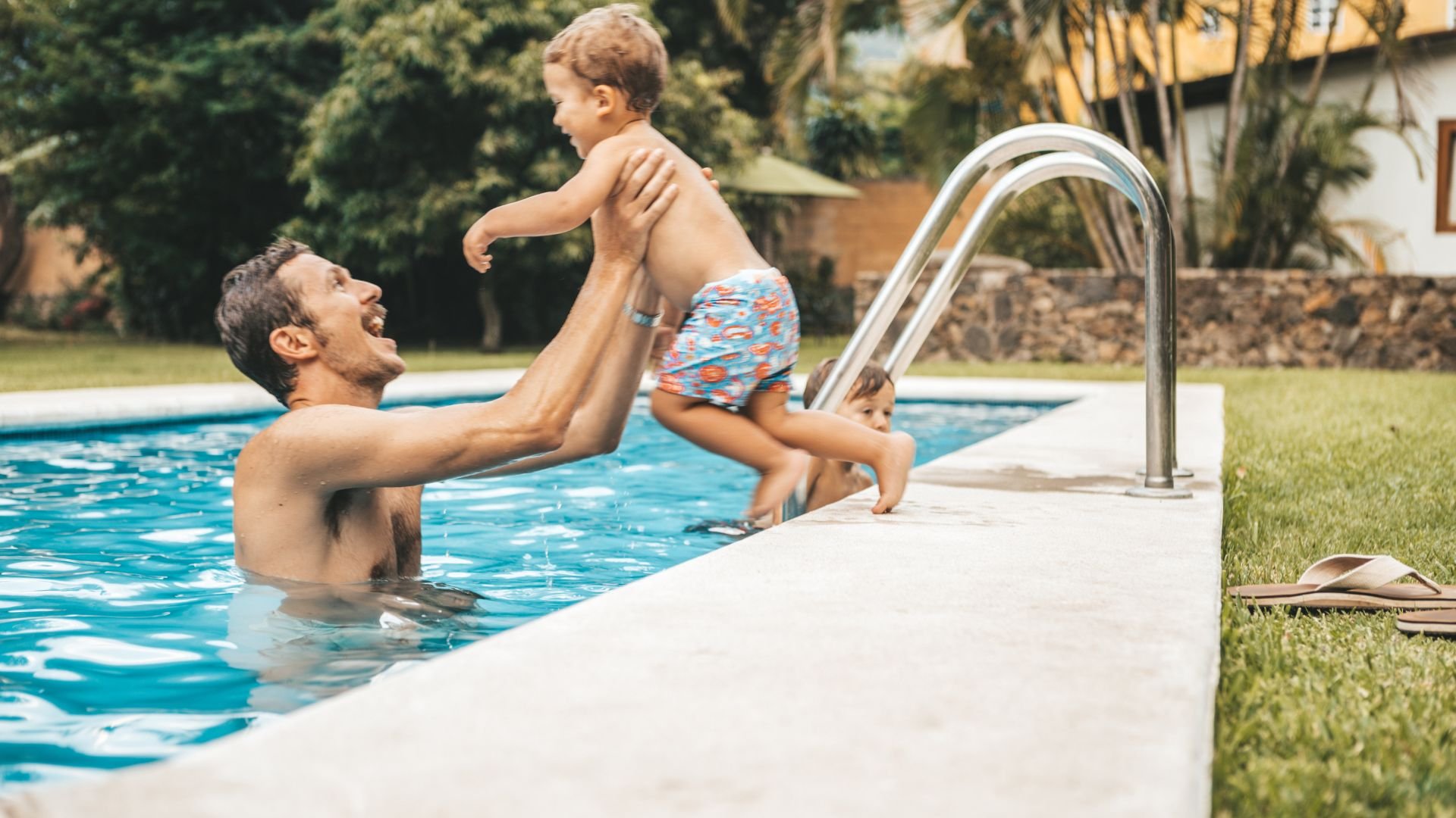 Parent playing with child in swimming pool on a sunny day